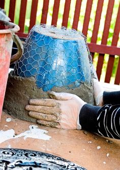 a person with gloves on laying down next to a bucket and potted planter