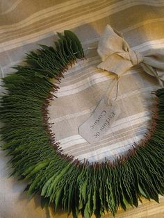 a close up of a wreath made out of grass on a bed with a ribbon