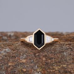 a black and white diamond ring sitting on top of a rock