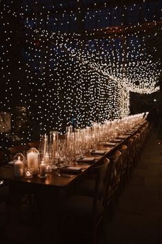 a long table is set with candles and wine glasses for an elegant dinner or party