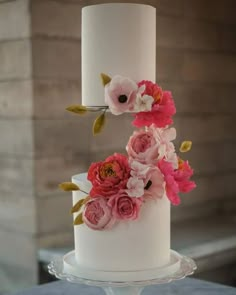 a three tiered white cake with pink flowers on top