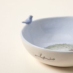 a blue bird figurine sitting on top of a bowl