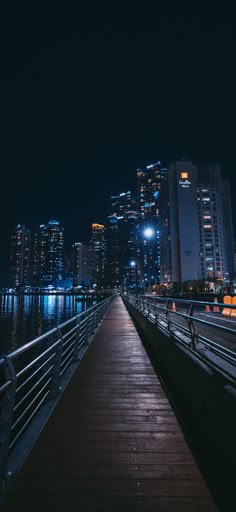 a long wooden walkway leading to the city at night