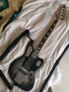 an electric bass guitar laying on top of a bed