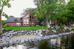 a large house sitting on top of a lush green field next to a river filled with rocks