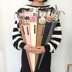 a woman holding a bunch of different types of pens in her hands and posing for the camera