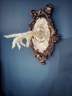 an ornate mirror with a spoon sticking out of it's center and the wall is painted blue