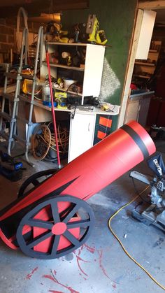 a large red object sitting on top of a floor next to a metal pipe and some tools