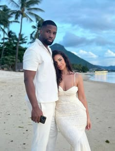 a man and woman posing for a photo on the beach