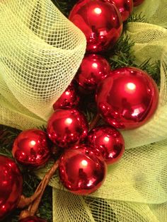 some red ornaments are hanging on a tree