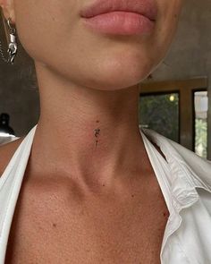 a woman with a small cross tattoo on her left side of the neck and chest