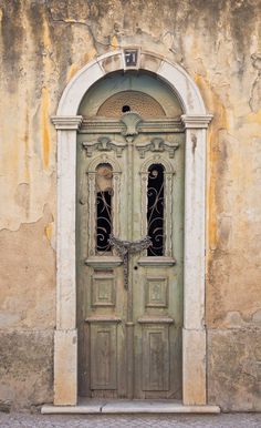 an old door with two glass windows in front of a stone wall and stucco building