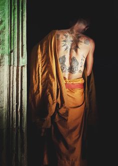 a man with tattoos on his back standing in a doorway