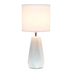 a table lamp with a white shade on the base and a light in front of it