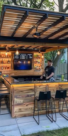 an outdoor bar with stools and tables under the roof is lit up by lights