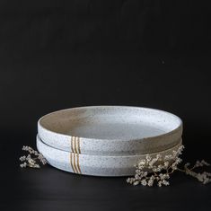 three white bowls with gold stripes and flowers in them on a black tableclothed surface