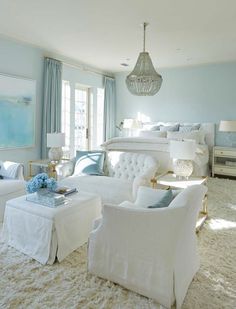 a living room filled with white furniture and blue walls