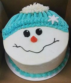 a cake decorated like a snowman with blue frosting on it's face