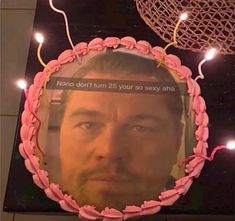 there is a cake with a man's face on it and string lights behind it