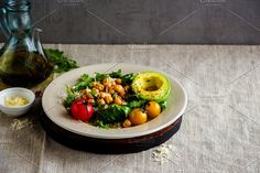 a salad with avocado, tomatoes and chickpeas on a white plate