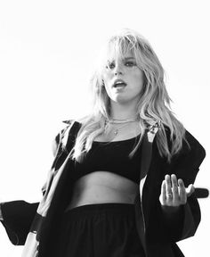 a black and white photo of a woman with her hands in the air while wearing a crop top