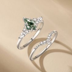 two engagement rings with green and white diamonds on them, one is shaped like an arrow