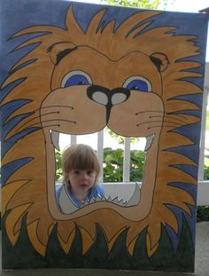 a little boy sitting in front of a cardboard cut out of a lion's head