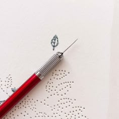 a red pen sitting on top of a white piece of paper next to a hole punch