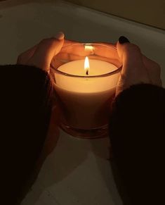 a person holding a lit candle in their hands