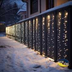 a fence covered in snow with lights on it