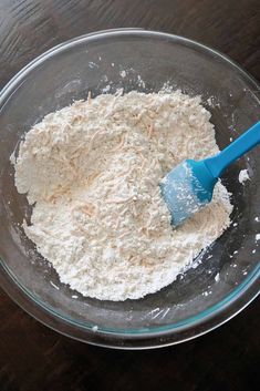 a glass bowl filled with flour on top of a wooden table