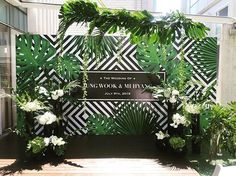 an outdoor wedding ceremony setup with greenery and white flowers on the side, in front of a black and white backdrop