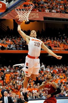 a basketball player jumping up to dunk the ball in front of an orange and white crowd