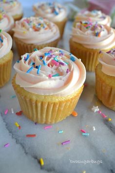 several cupcakes with white frosting and sprinkles