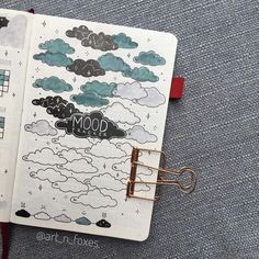 an open notebook with clouds and the words mood written in black on it, sitting on a blue carpet