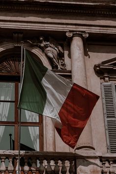 the italian flag is flying in front of an old building