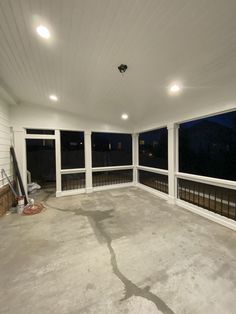 an empty room with large windows and no curtains on the ceiling, is shown at night