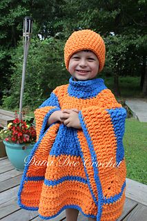 a young boy wearing an orange and blue crocheted blanket on top of a wooden deck