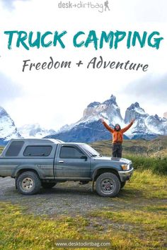 a man standing on top of a truck with his arms in the air and mountains behind him