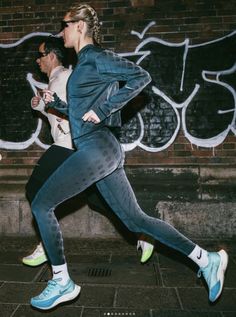 a woman running on the street in front of graffiti