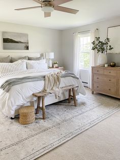 a bedroom with a bed, dressers and ceiling fan in the middle of it