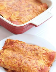 an omelet is on a white plate next to a red casserole dish