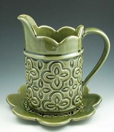 a green coffee cup and saucer sitting on top of a saucer with an ornate design