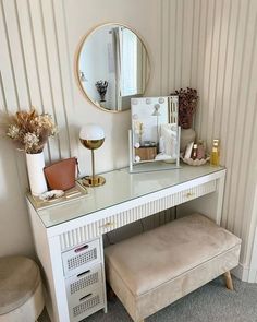 a white desk with a mirror, stool and vases on the wall next to it