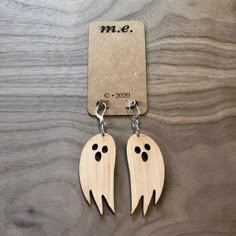 two wooden ghost shaped earrings with black eyes and fangs on them, hanging from a key chain