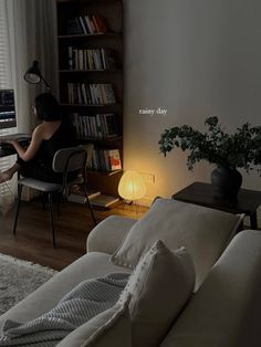 a woman sitting in front of a computer on top of a desk next to a book shelf