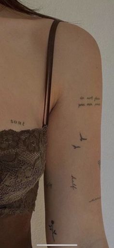 a woman's arm with writing on it and birds in the sky behind her