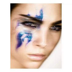 a woman's face with blue and white paint on her face, as if she is looking at the camera