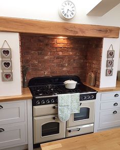 a kitchen with an oven, stove and wooden counter tops in front of a brick wall