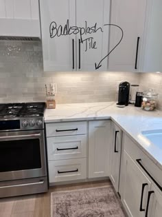 a kitchen with white cabinets and stainless steel appliances, including a silver stove top oven